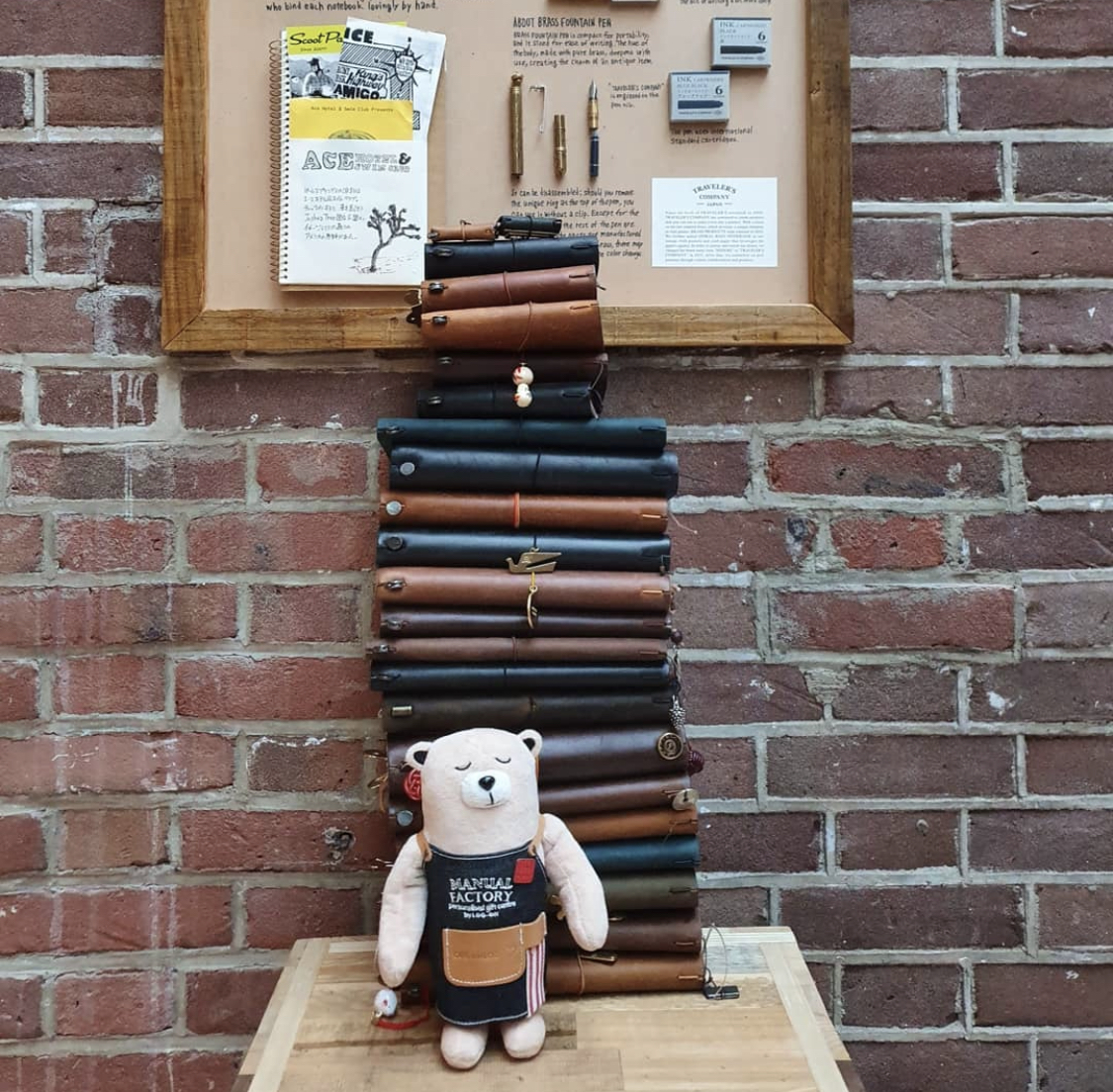 A stack of journals next to the Manual Factory Bear plush toy